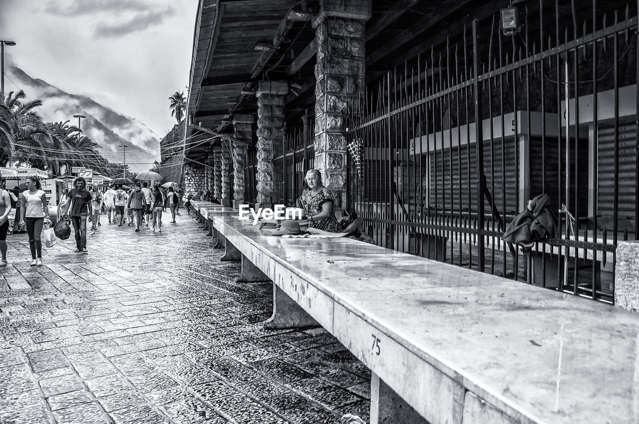 PEOPLE WALKING ON STREET BY BUILDINGS IN CITY