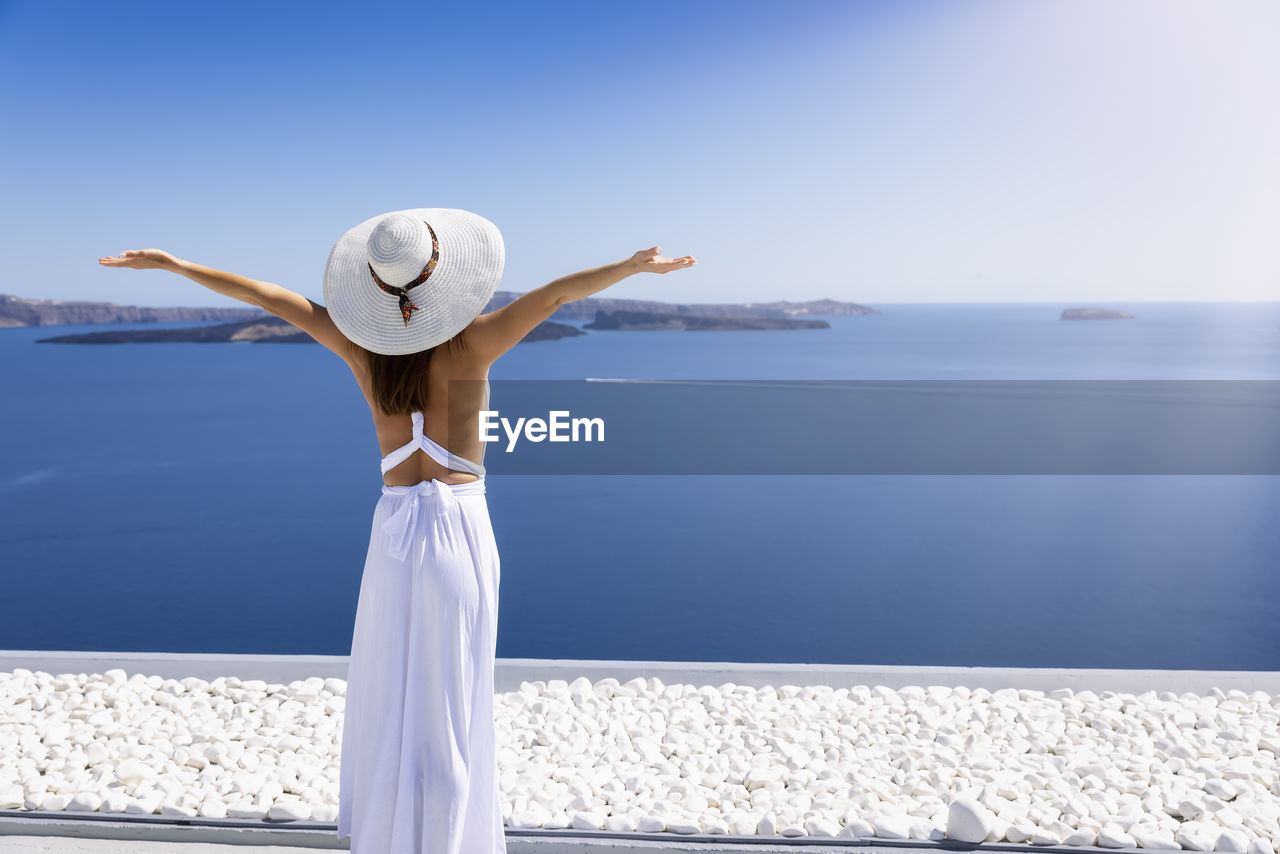 Rear view of woman with arms outstretched looking at sea