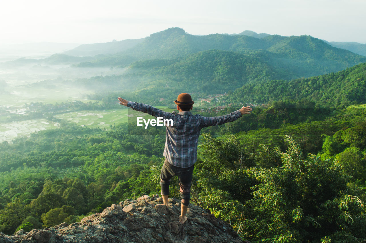 Man standing on cliff against landscape