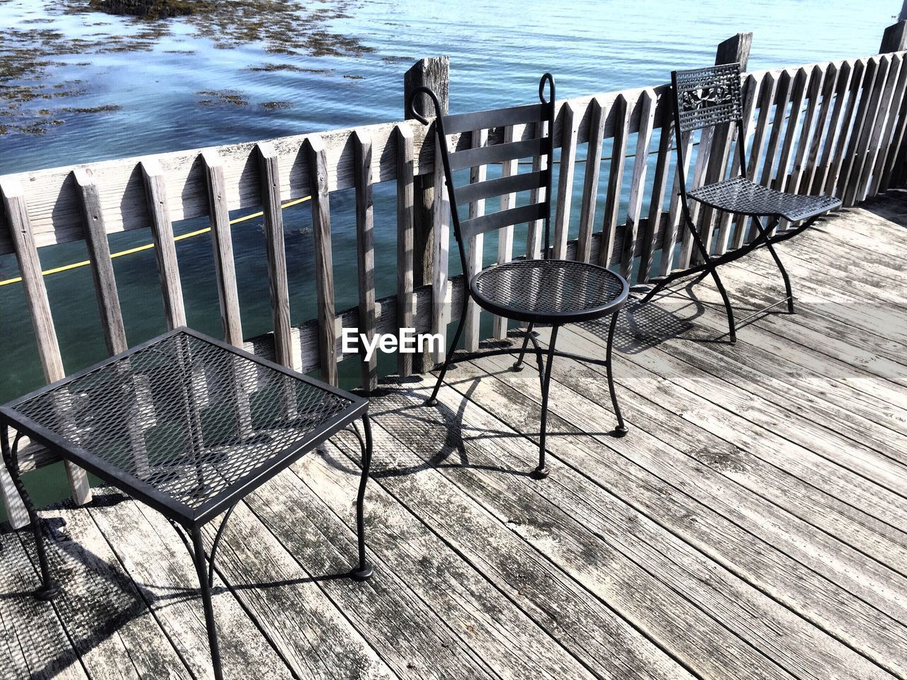 High angle view of empty chairs on boardwalk by lake