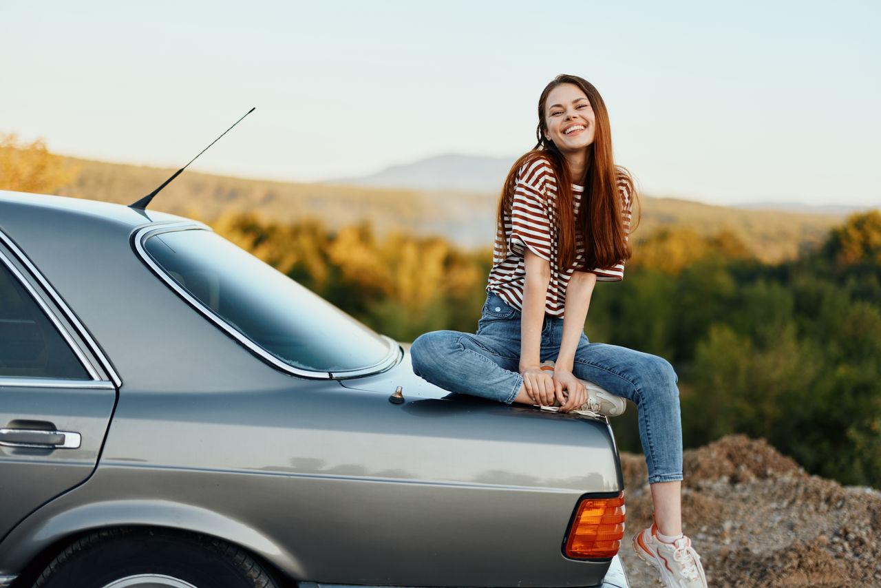 portrait of young woman standing against car