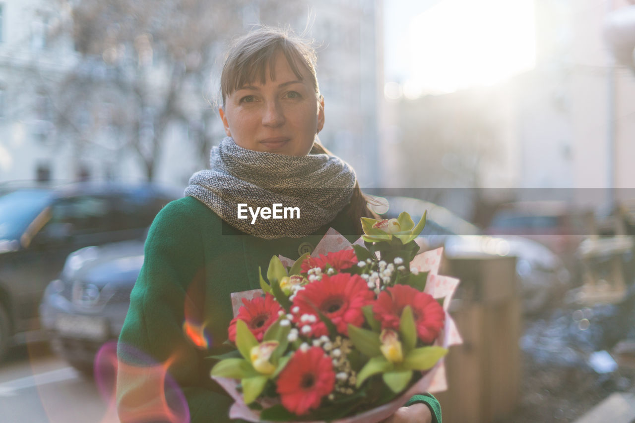 CLOSE-UP OF YOUNG WOMAN WITH RED FLOWER IN BACKGROUND