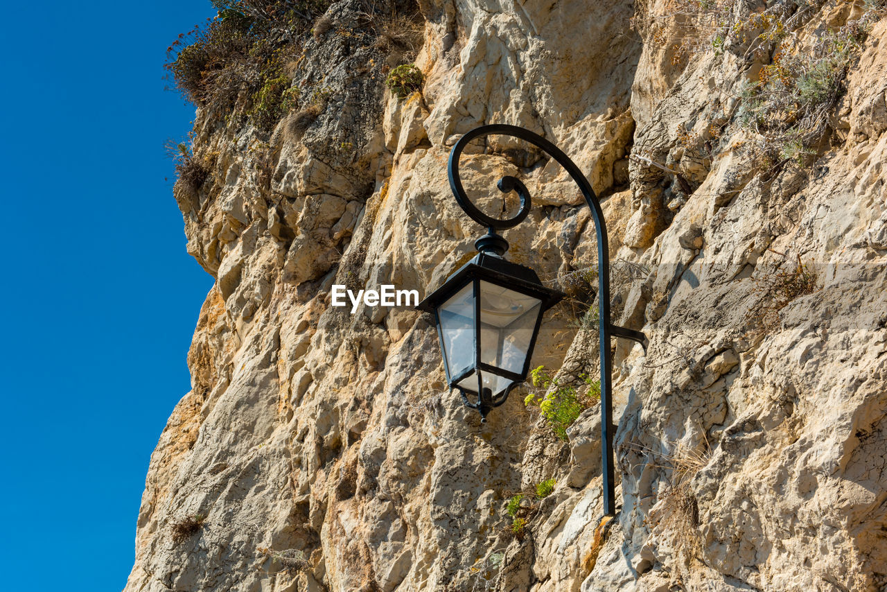 Low angle view of lighthouse on cliff against clear sky