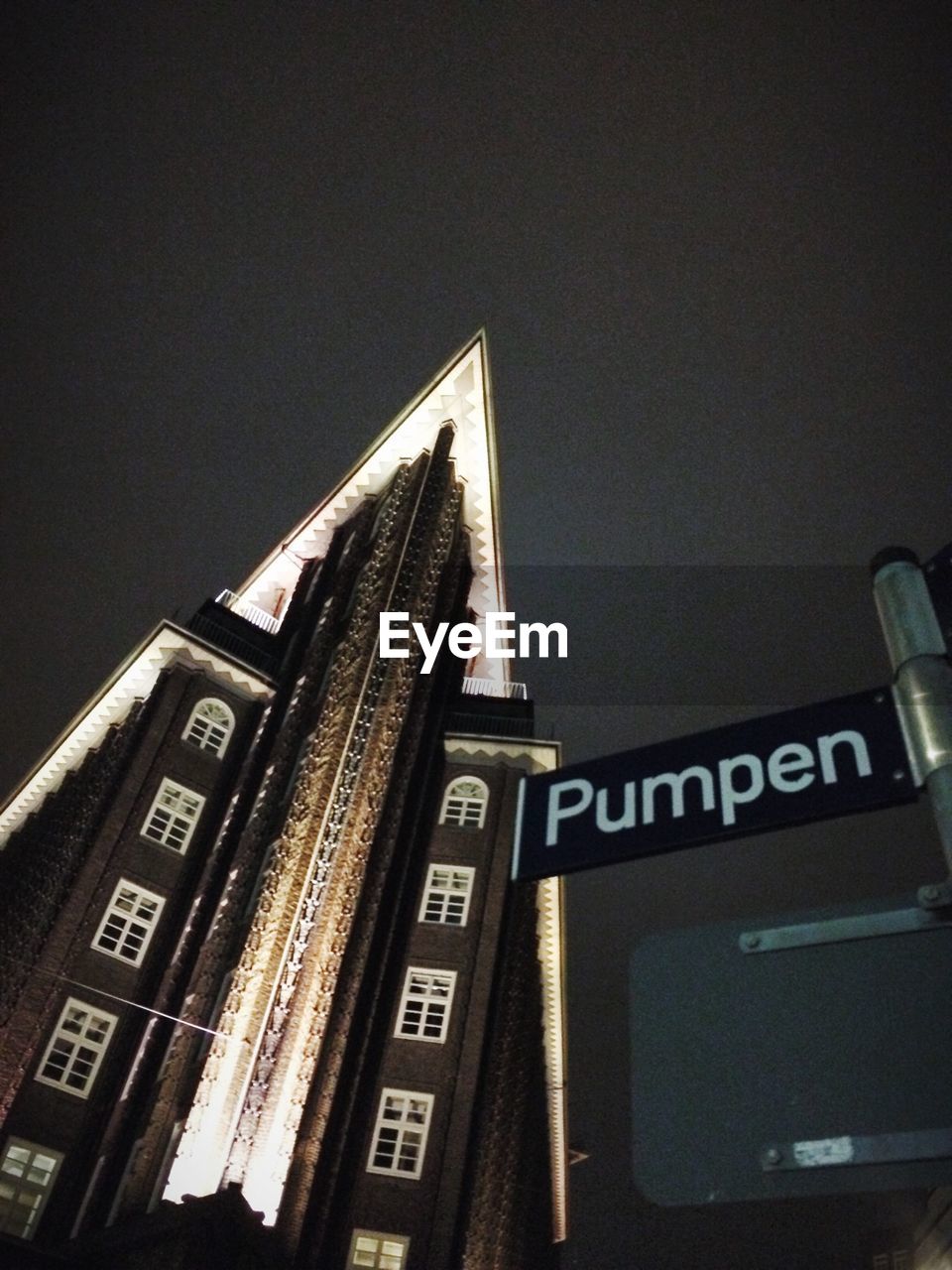 Low angle view of signboard and building against clear sky at night