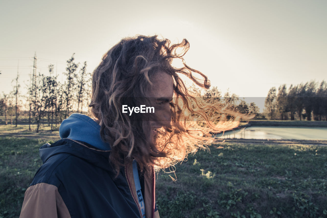 PORTRAIT OF WOMAN AGAINST SKY AT SUNSET
