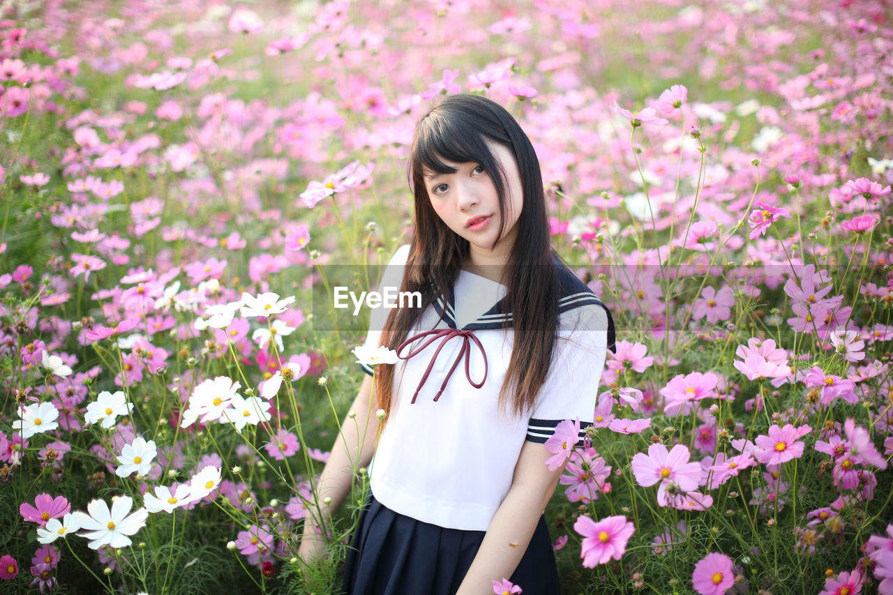 Portrait of woman standing amidst pink flowering plants