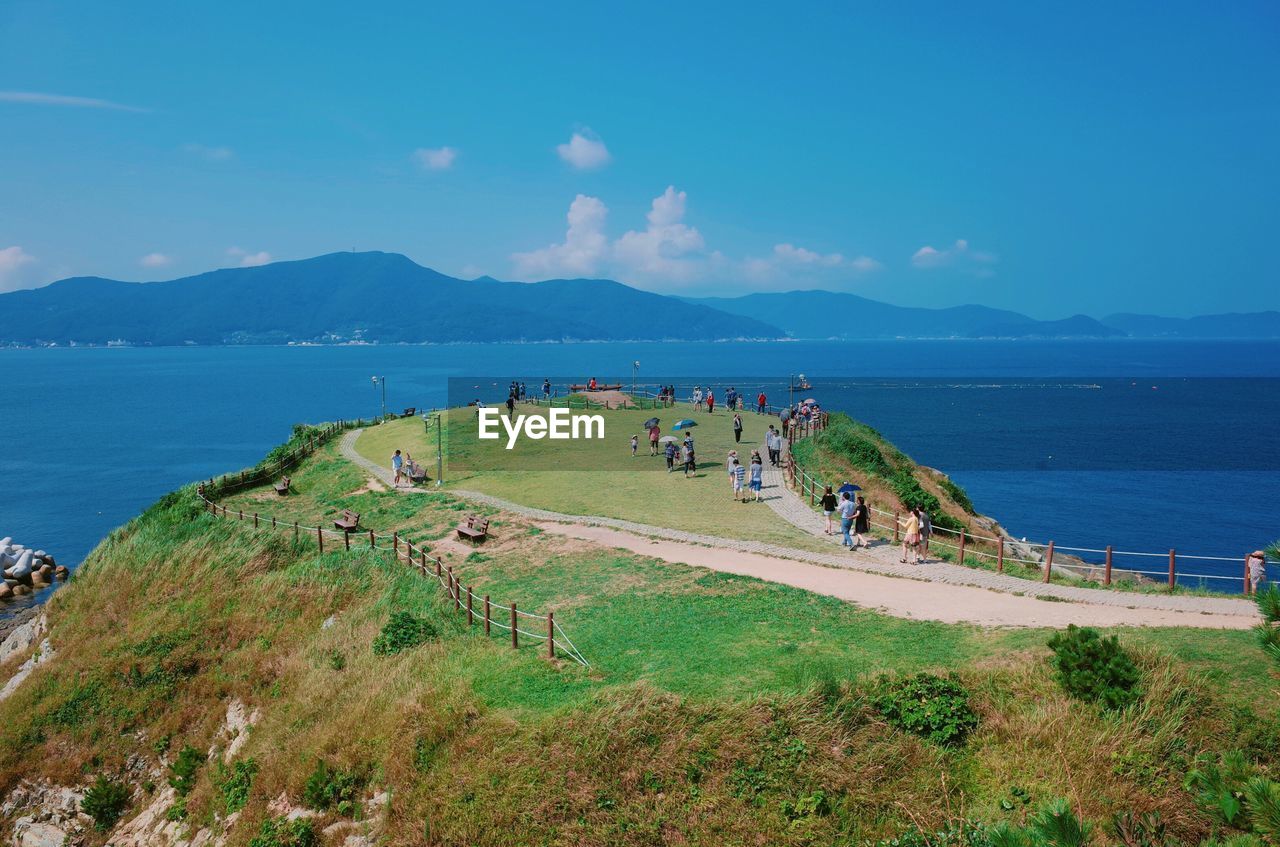 People on cliff by sea against sky