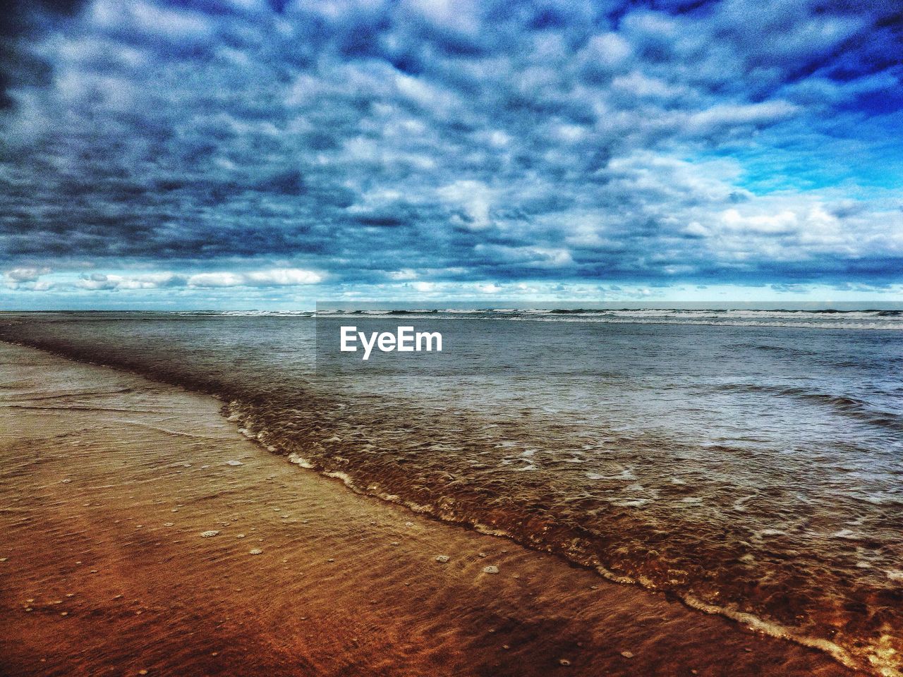 VIEW OF BEACH AGAINST CLOUDY SKY