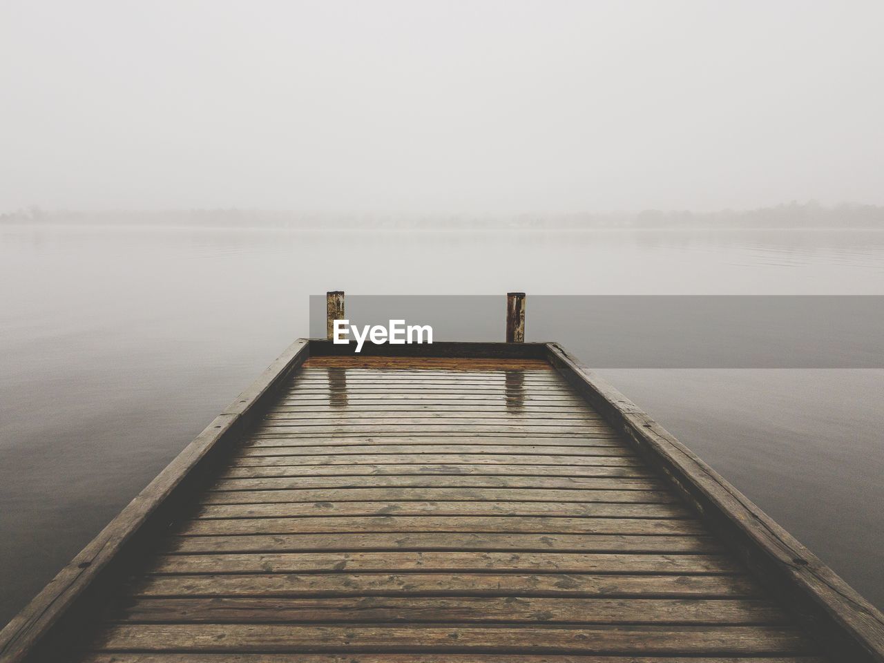 Pier over lake against sky during winter