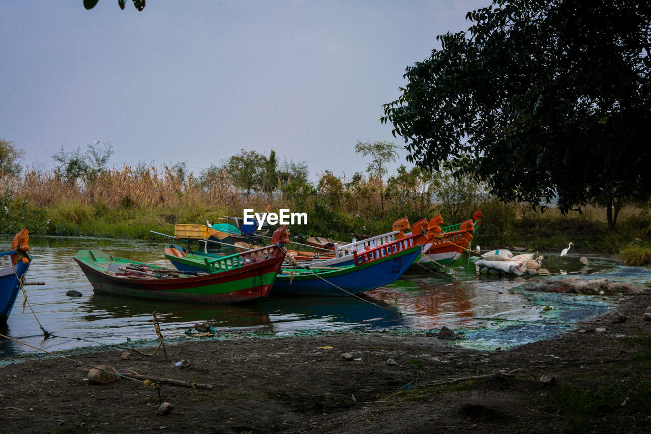 Boats moored on shore against sky