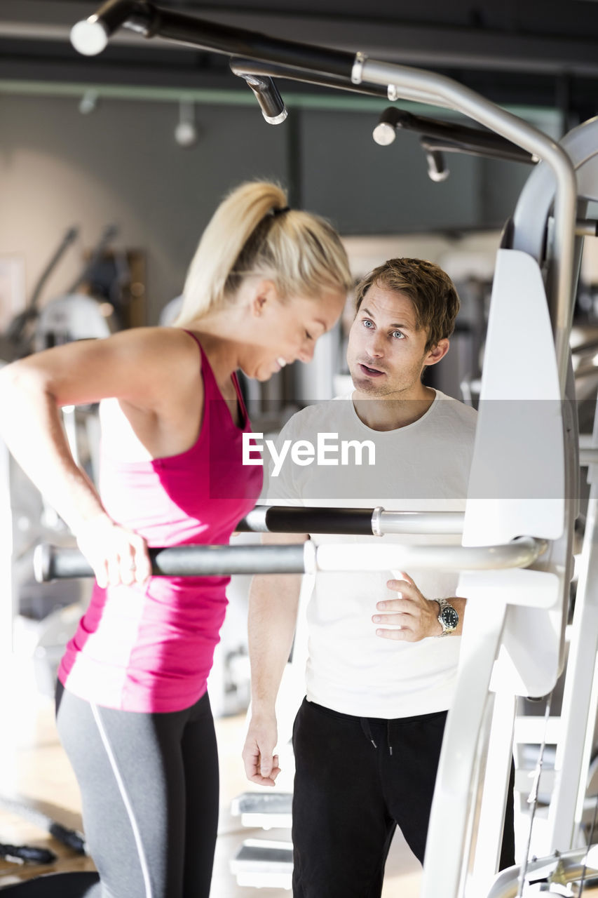 Instructor motivating customer exercising at gym