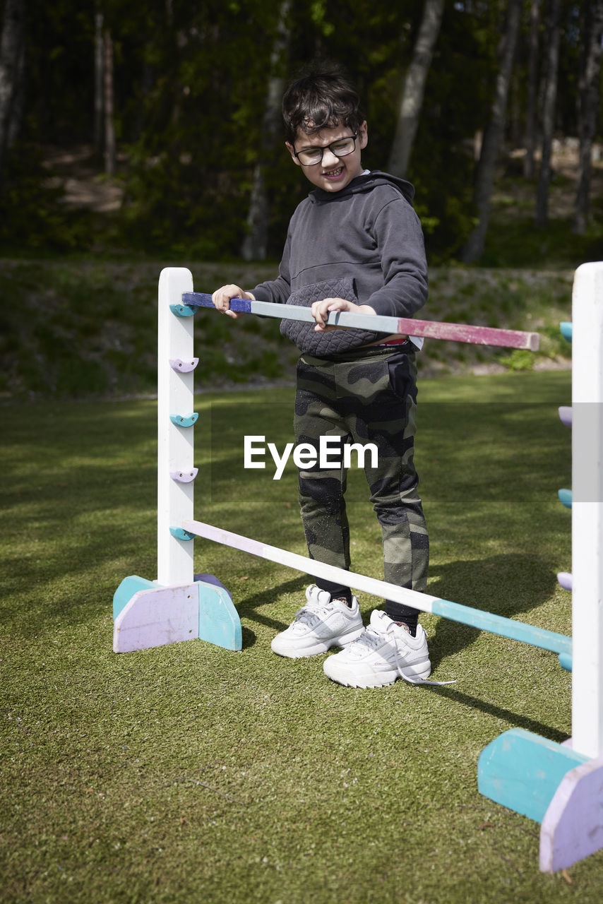 Boy adjusting hurdle at racing competition