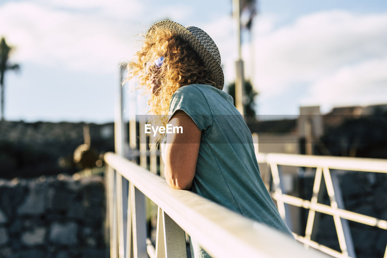 Side view of woman standing against railing