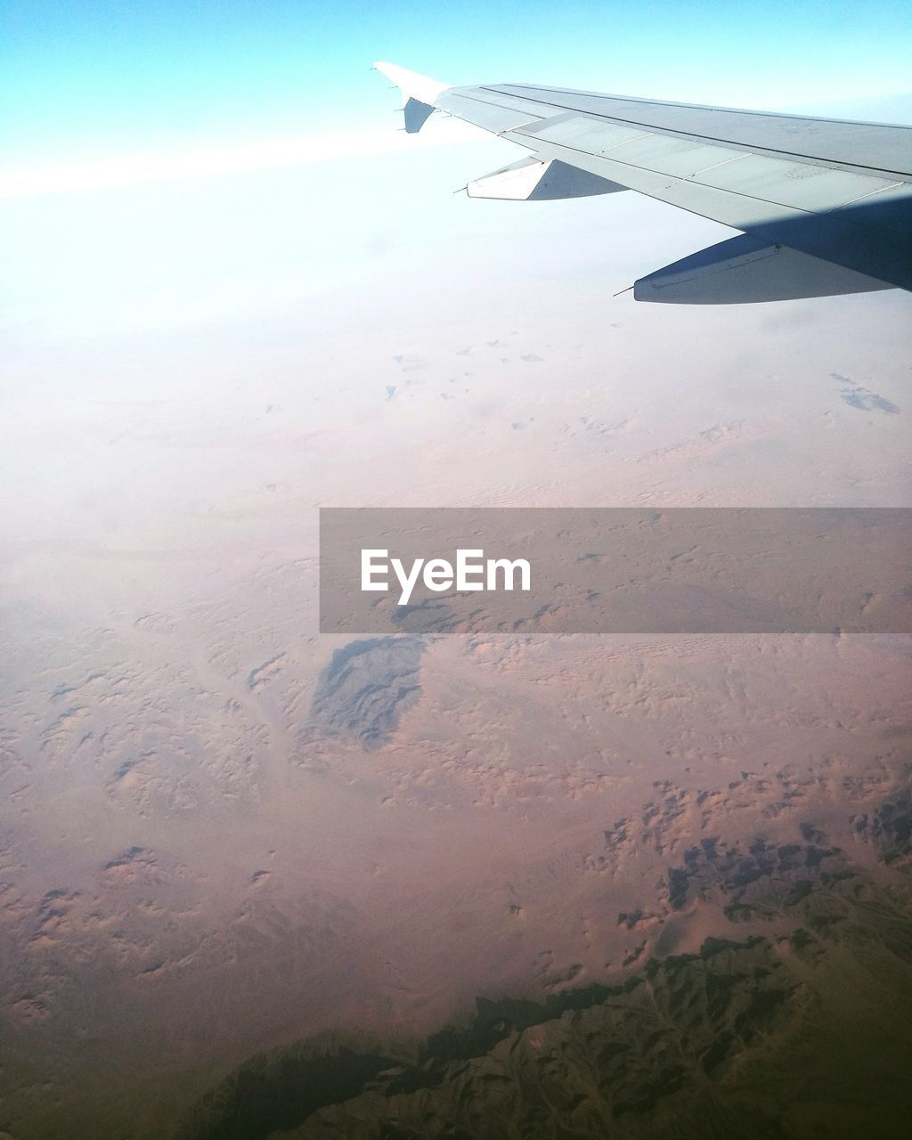 CROPPED IMAGE OF AIRPLANE WING OVER LANDSCAPE