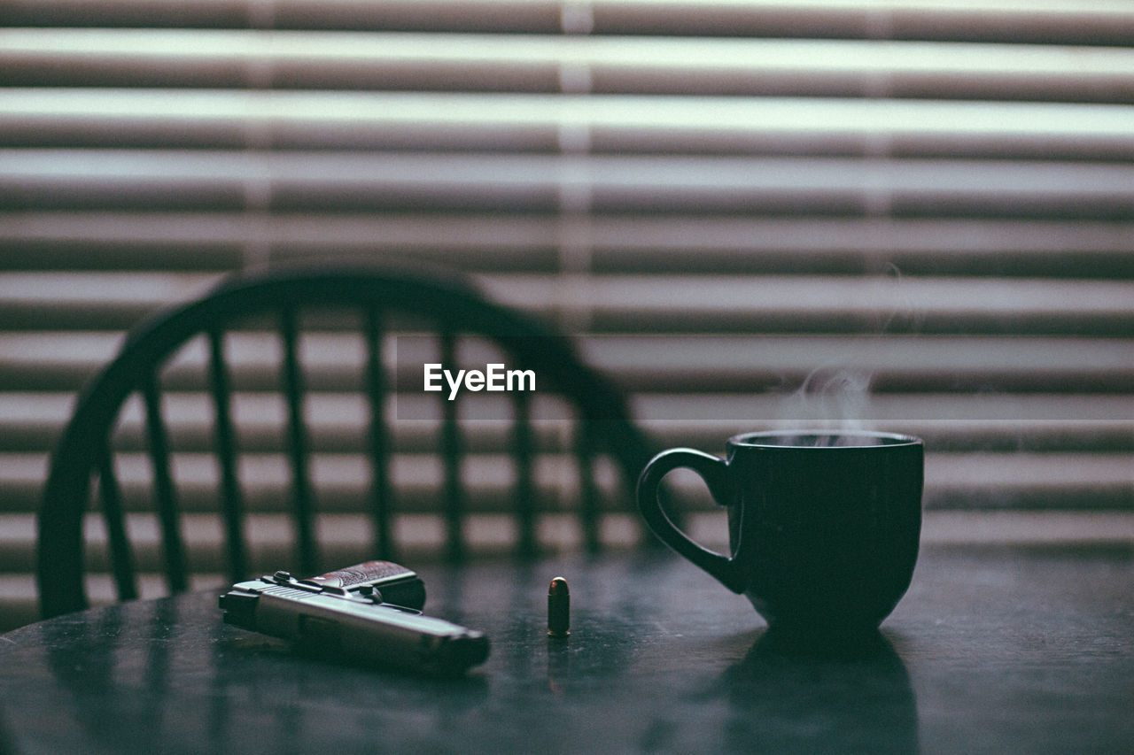 .45 handgun on dining room table alongside a steaming hot cup of coffee