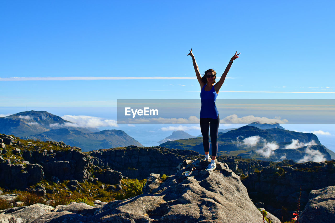 Full length of woman standing on mountain against sky