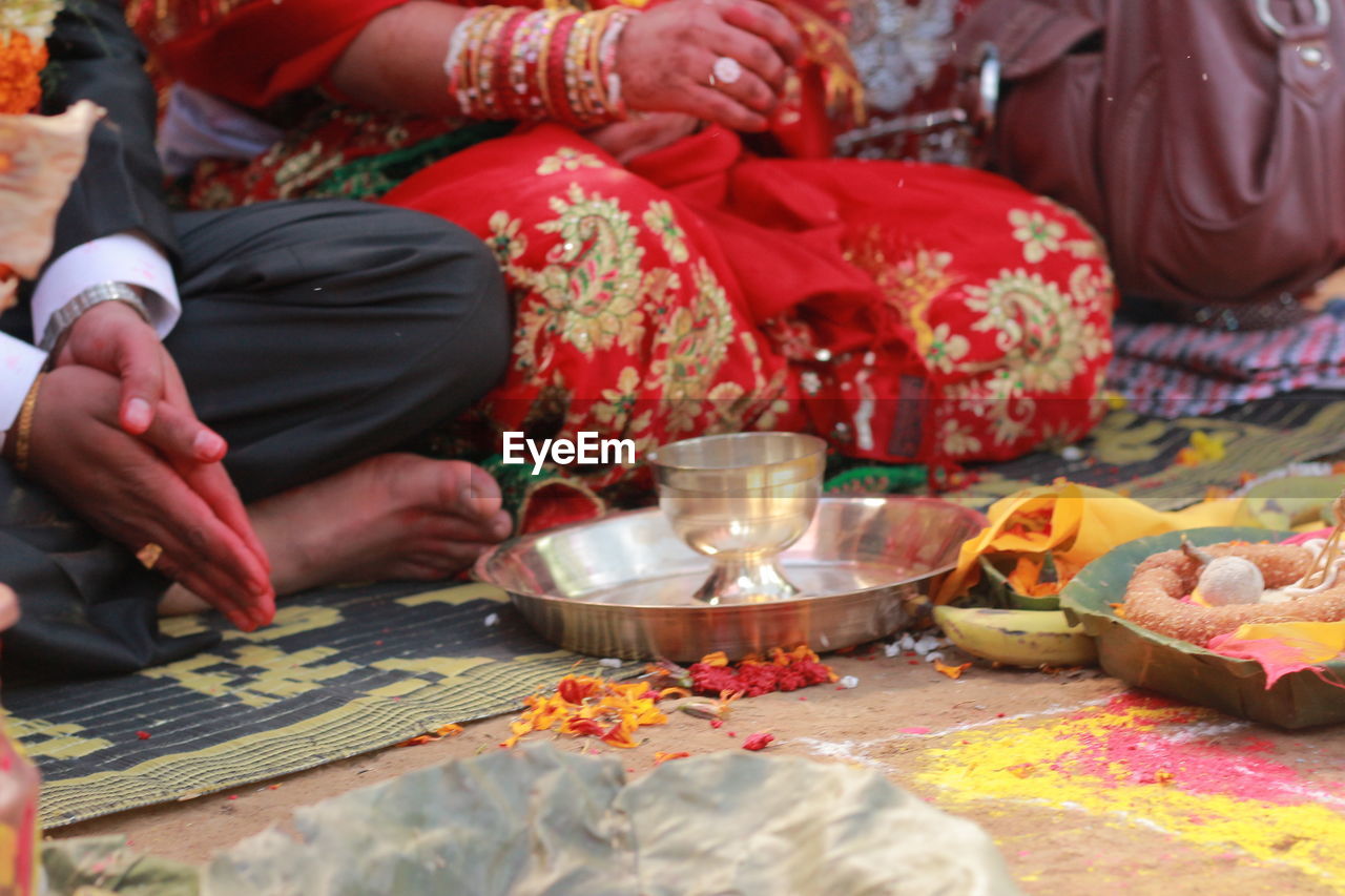 Midsection of bride and groom sitting during wedding ceremony