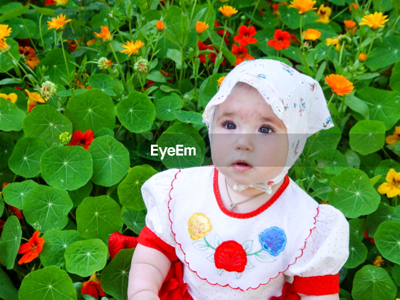 Close-up of cute baby girl looking away while standing by plants