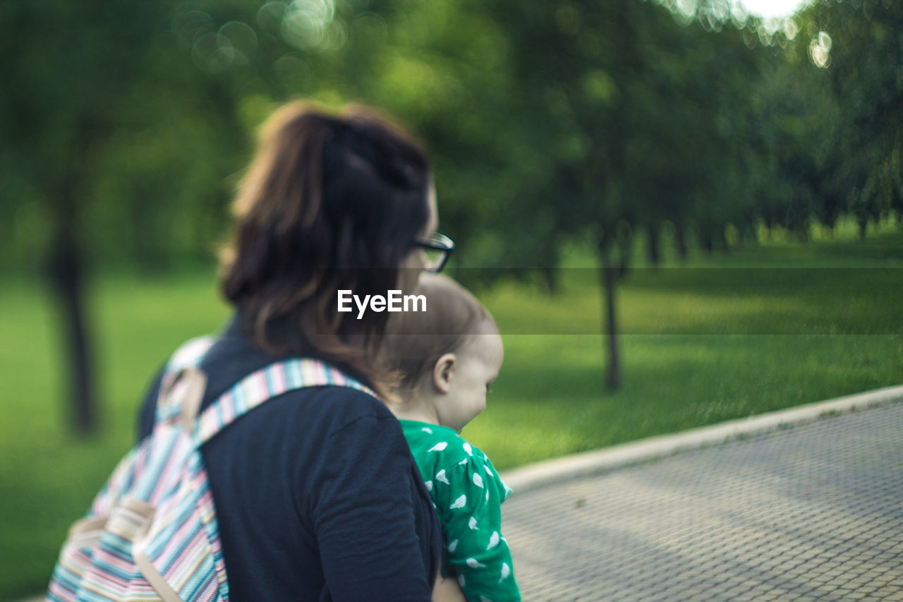 Mother with baby girl standing on footpath at park