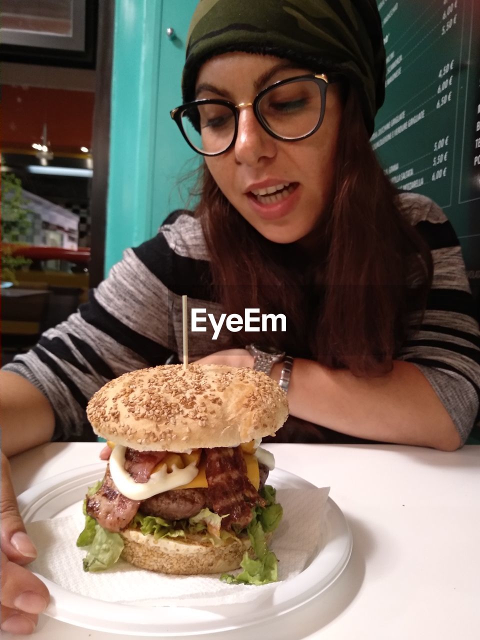 Young woman having burger at table in restaurant