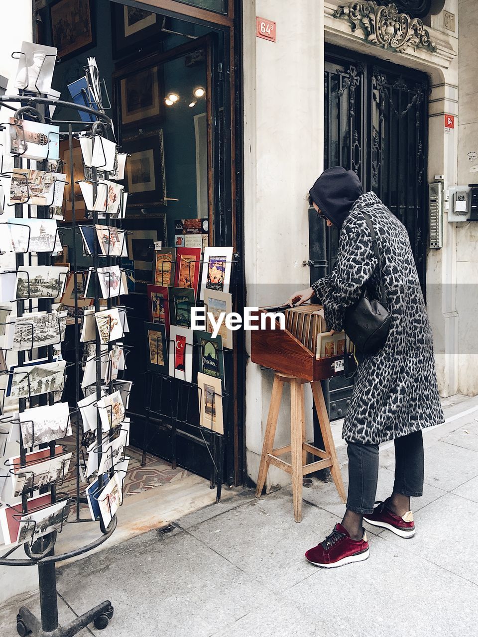 SIDE VIEW OF WOMAN STANDING BY STORE IN CITY