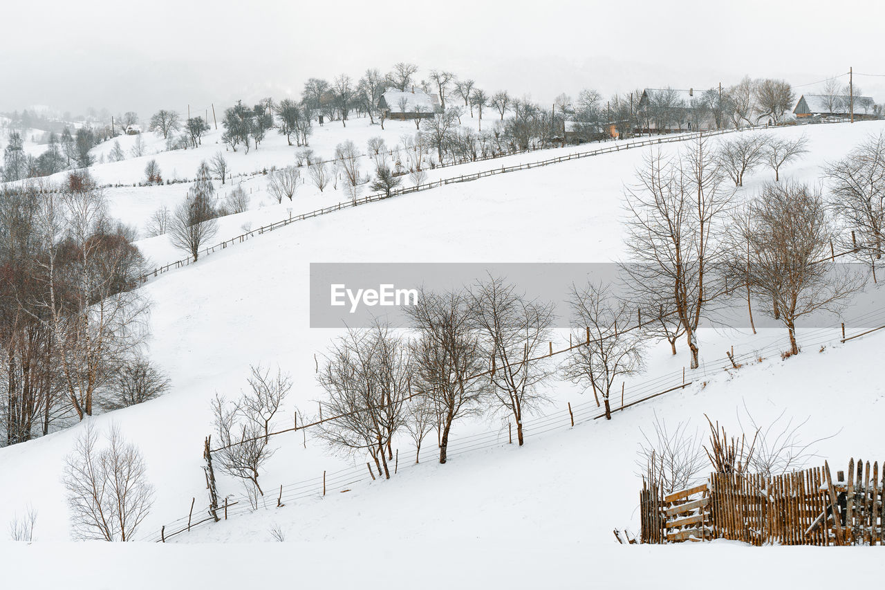 Scenic view of village on snowy hill in a winter day