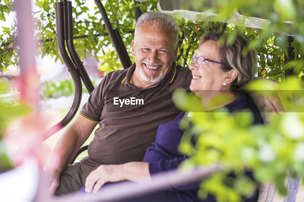 Portrait of smiling senior man sitting with woman on bench
