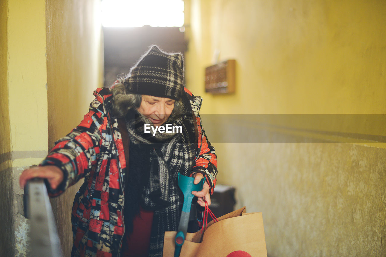 Senior east european disabled woman entering a building with an architectural barrier 