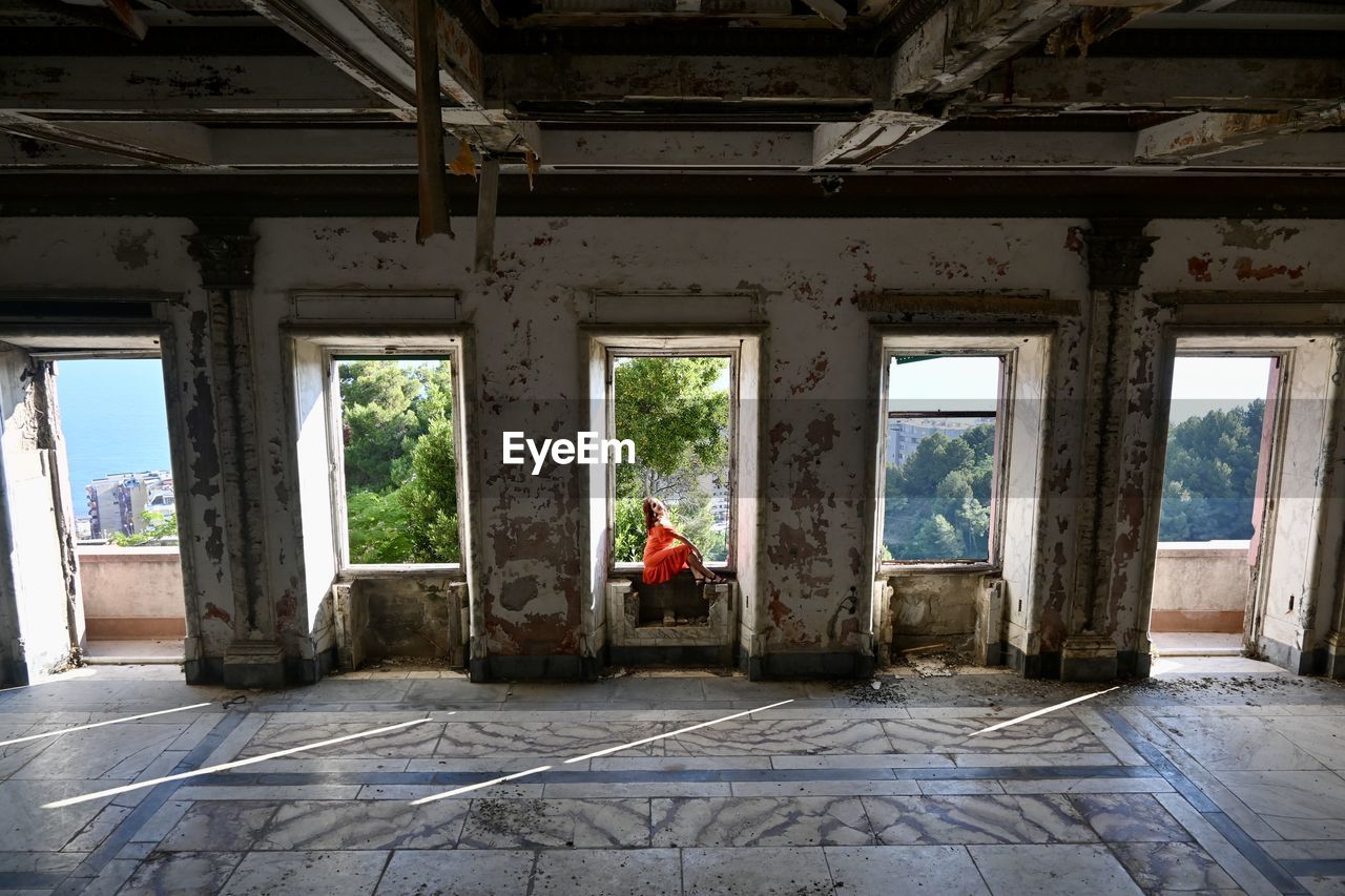 Rear view of woman sitting in abandoned building