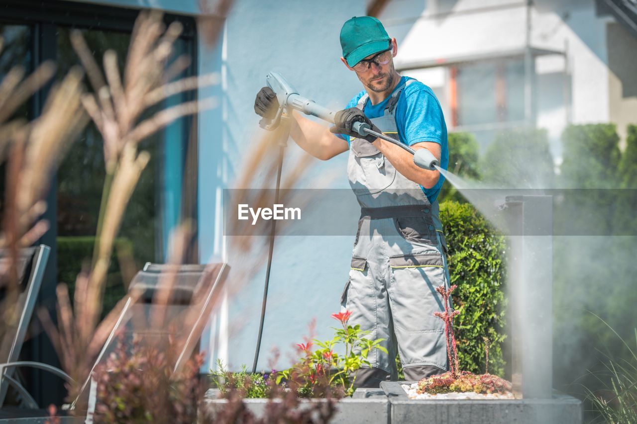 Man spraying water at backyard during sunny day