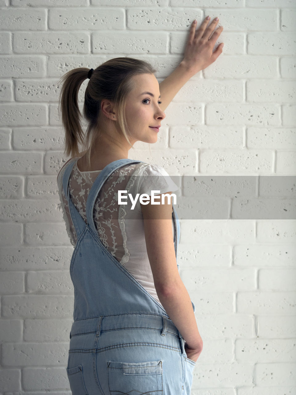 Rear view of thoughtful woman looking away while standing against wall