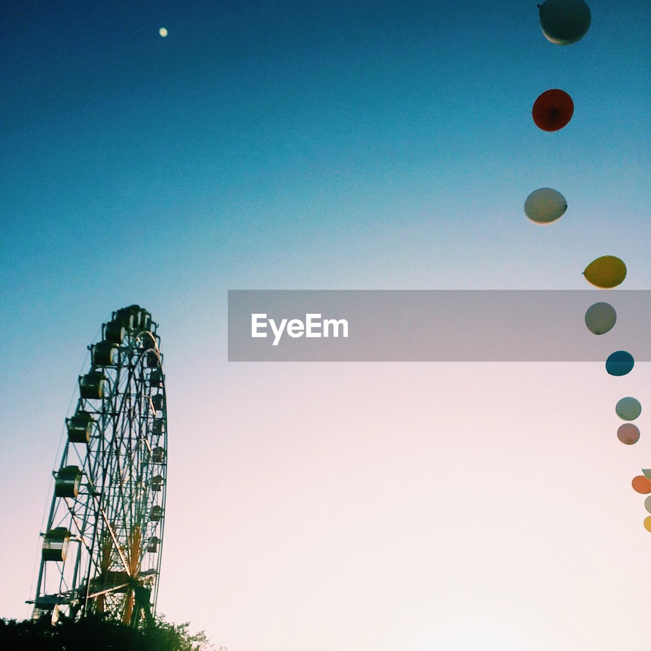 Low angle view of balloons and ferris wheel against clear sky