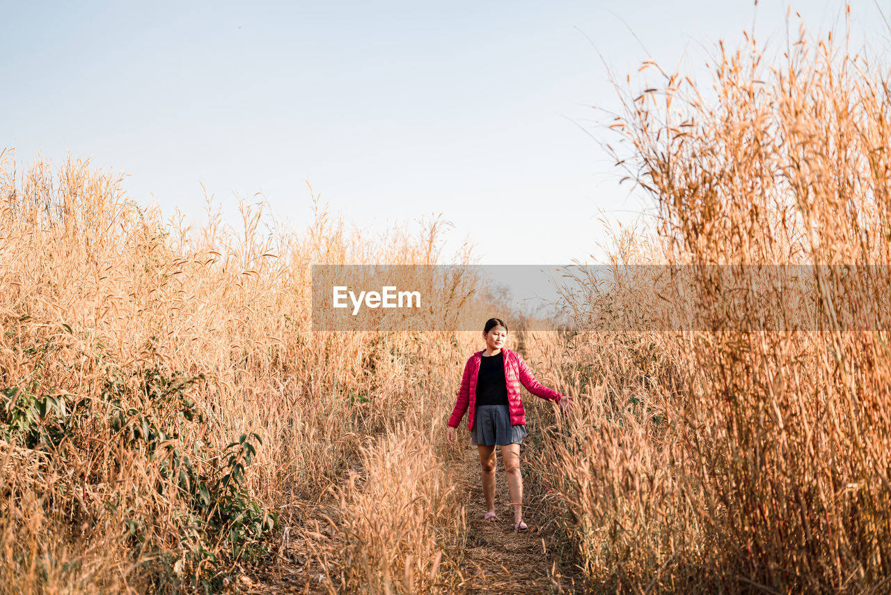 Woman walking on field against sky