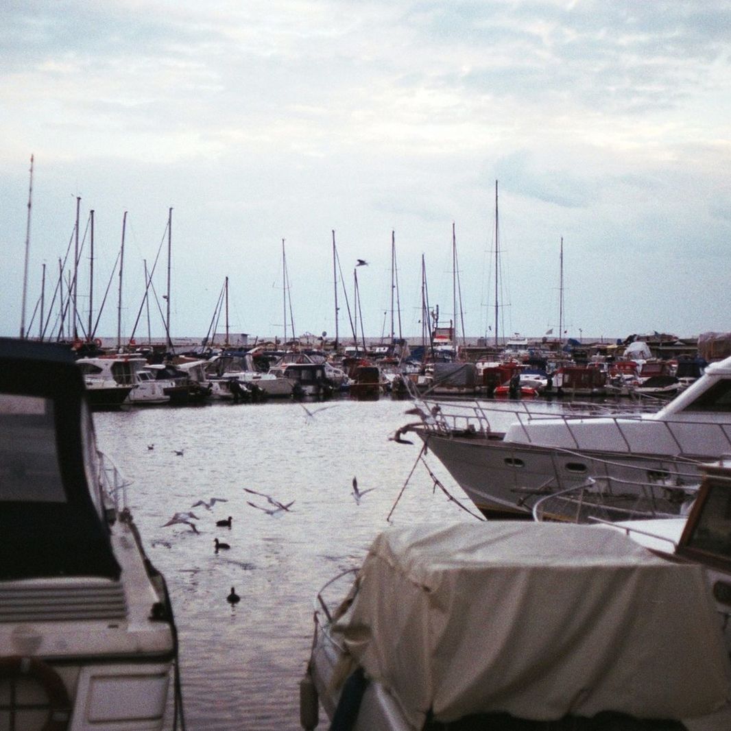 BOATS MOORED AT HARBOR AGAINST SKY