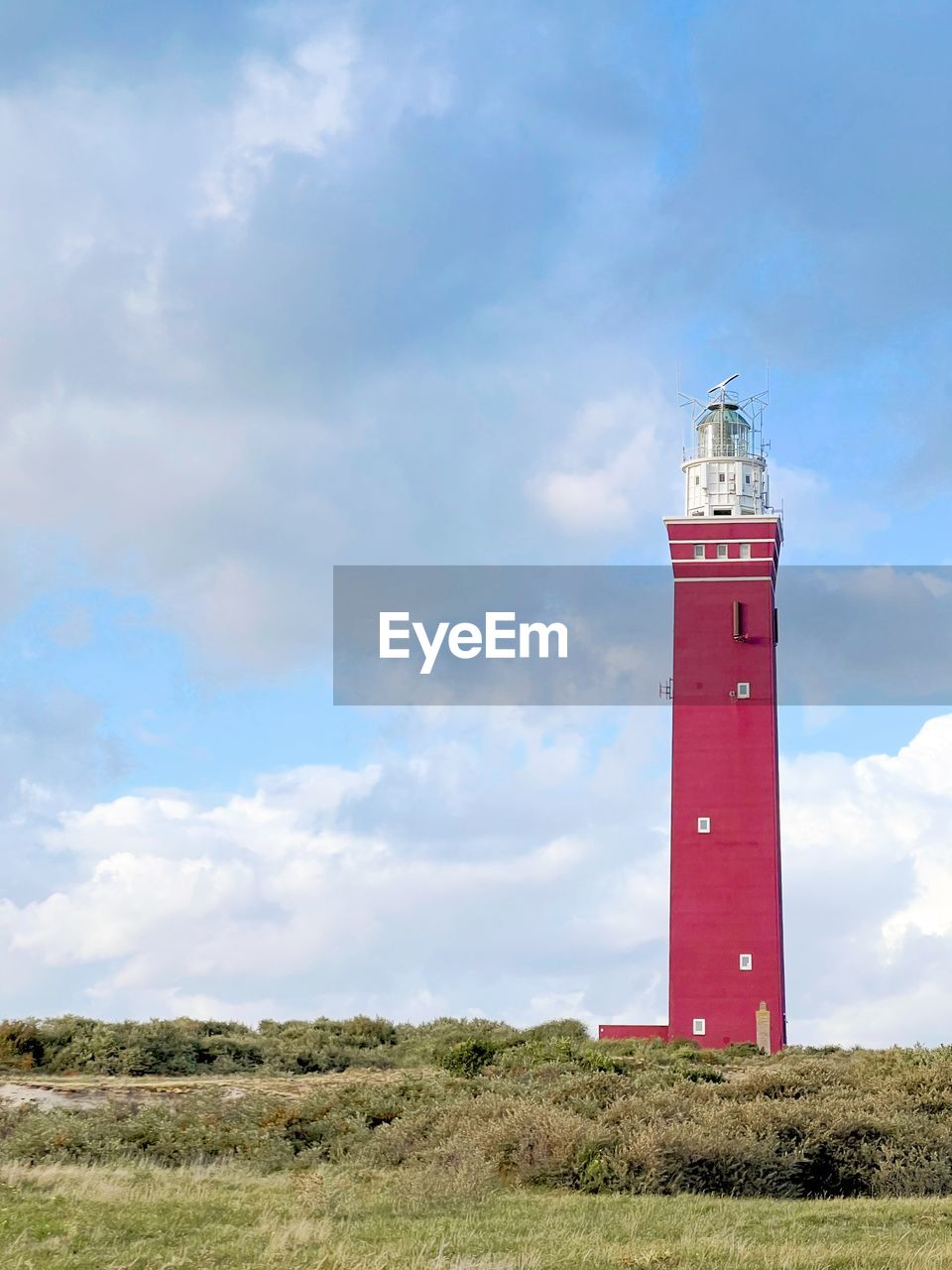 Lighthouse on field against sky