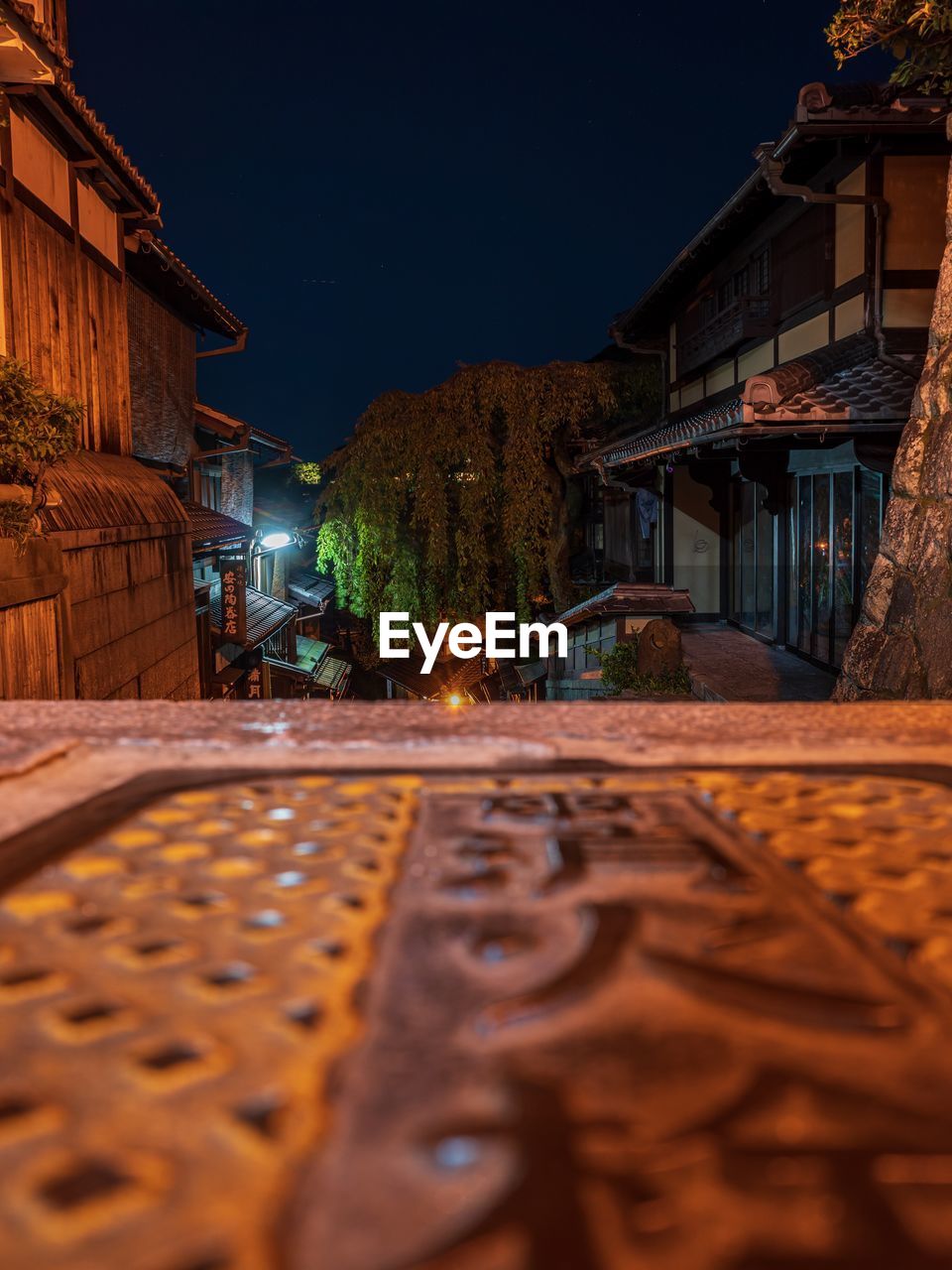 VIEW OF STREET AMIDST BUILDINGS AT NIGHT