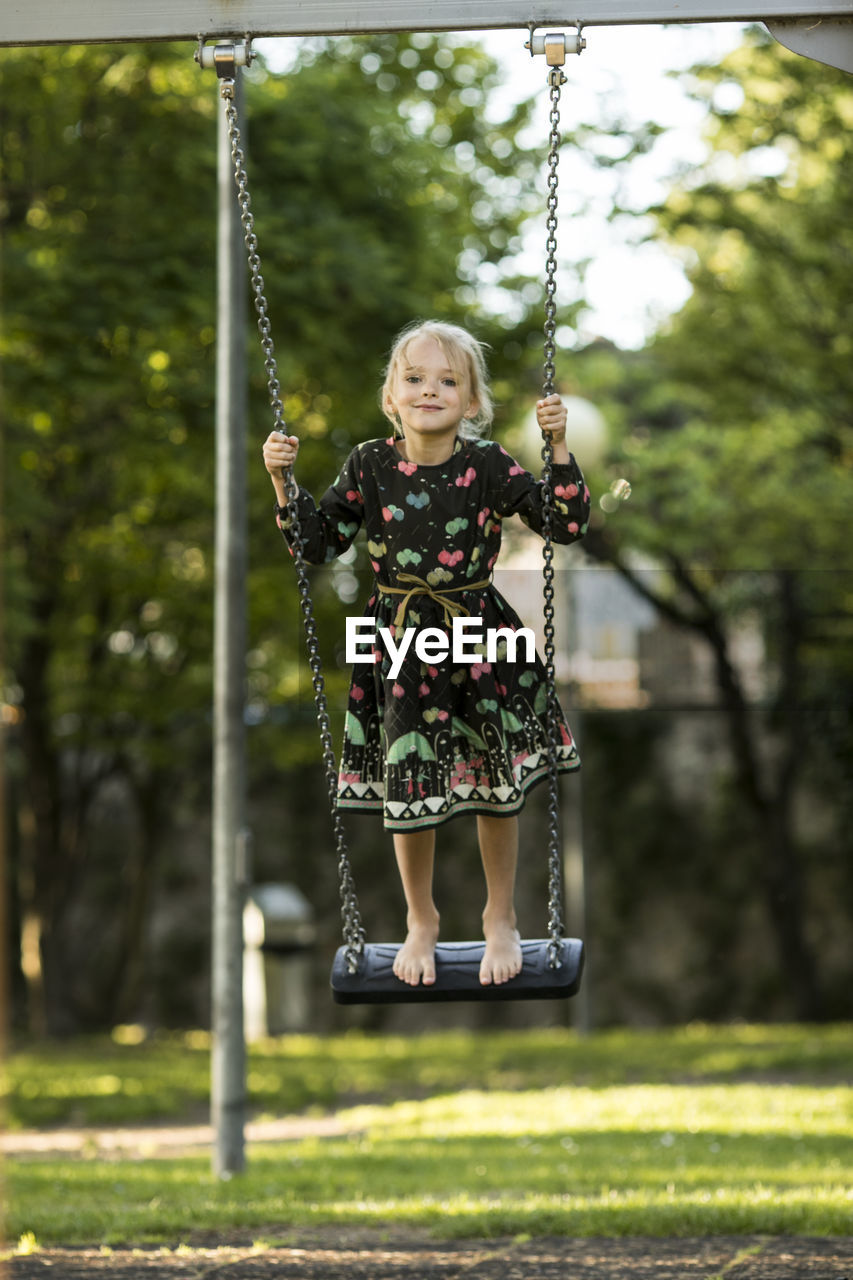 Portrait of smiling girl swinging on swing