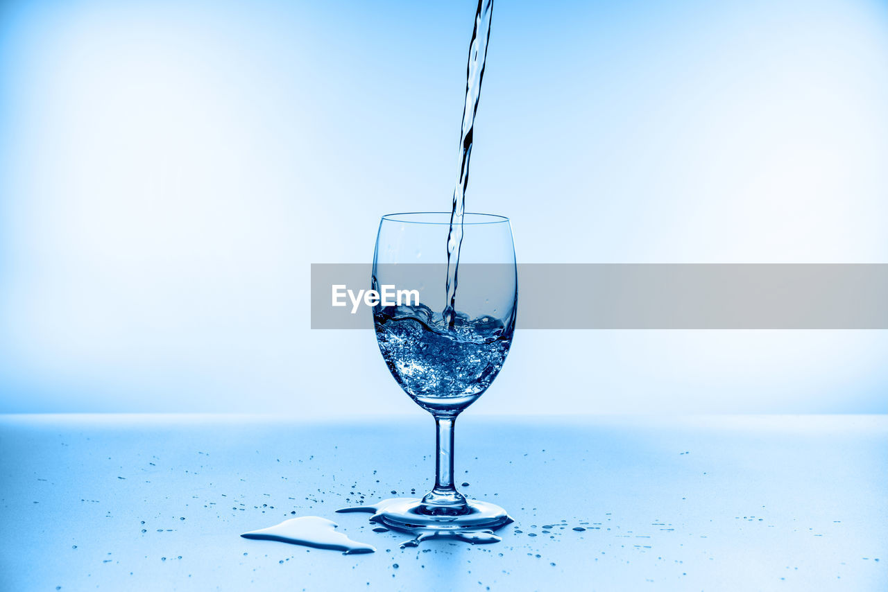 CLOSE-UP OF WINE GLASS AGAINST BLUE TABLE