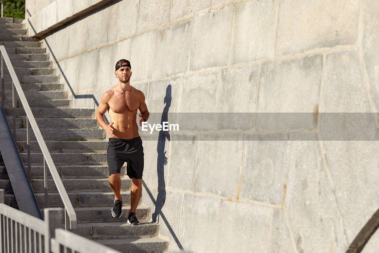 low angle view of shirtless man standing on steps