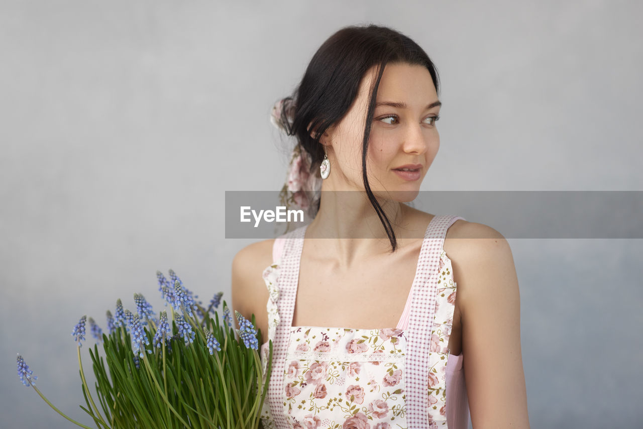 Smiling woman looking away while standing against wall