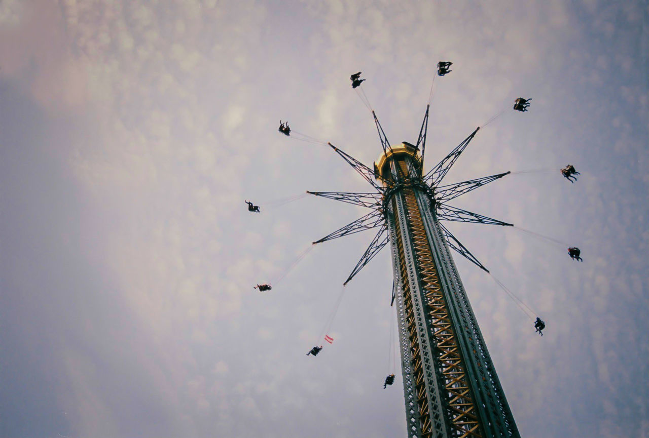 Low angle view of chain swing ride against cloudy sky