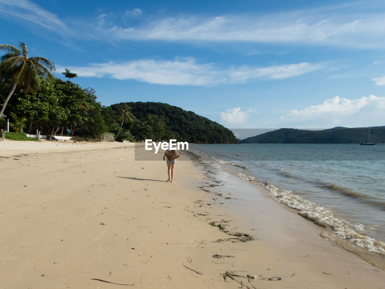 Woman walking at beach against sky