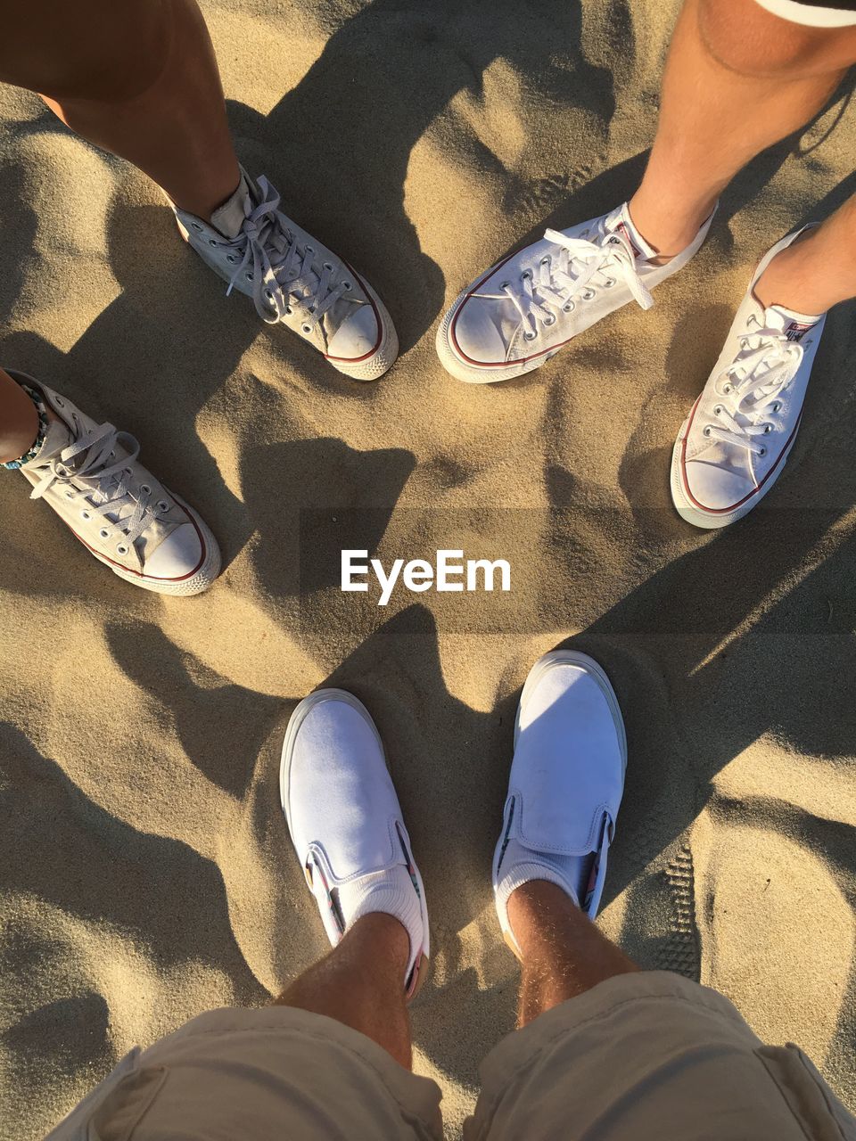 LOW SECTION OF FRIENDS STANDING ON SAND