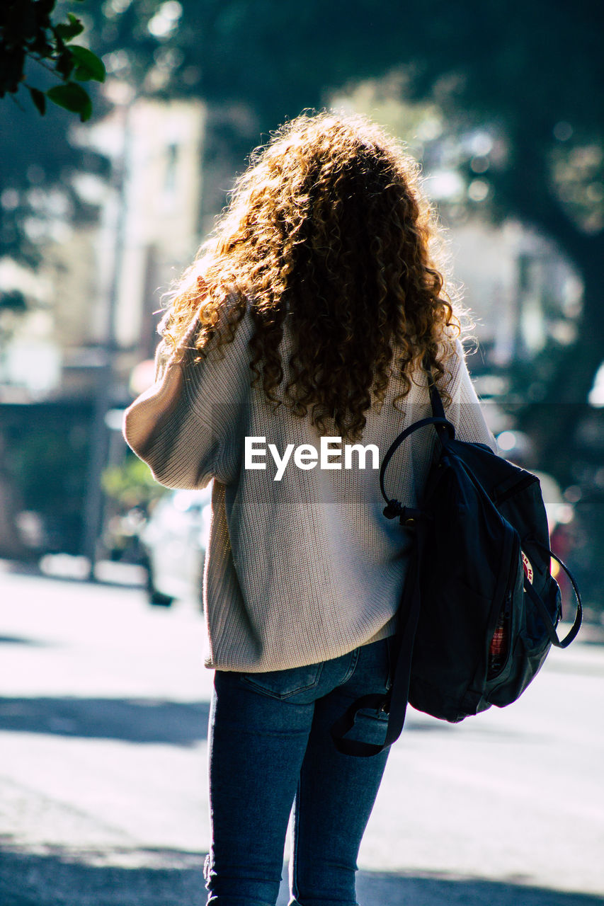 REAR VIEW OF WOMAN STANDING AGAINST CITY