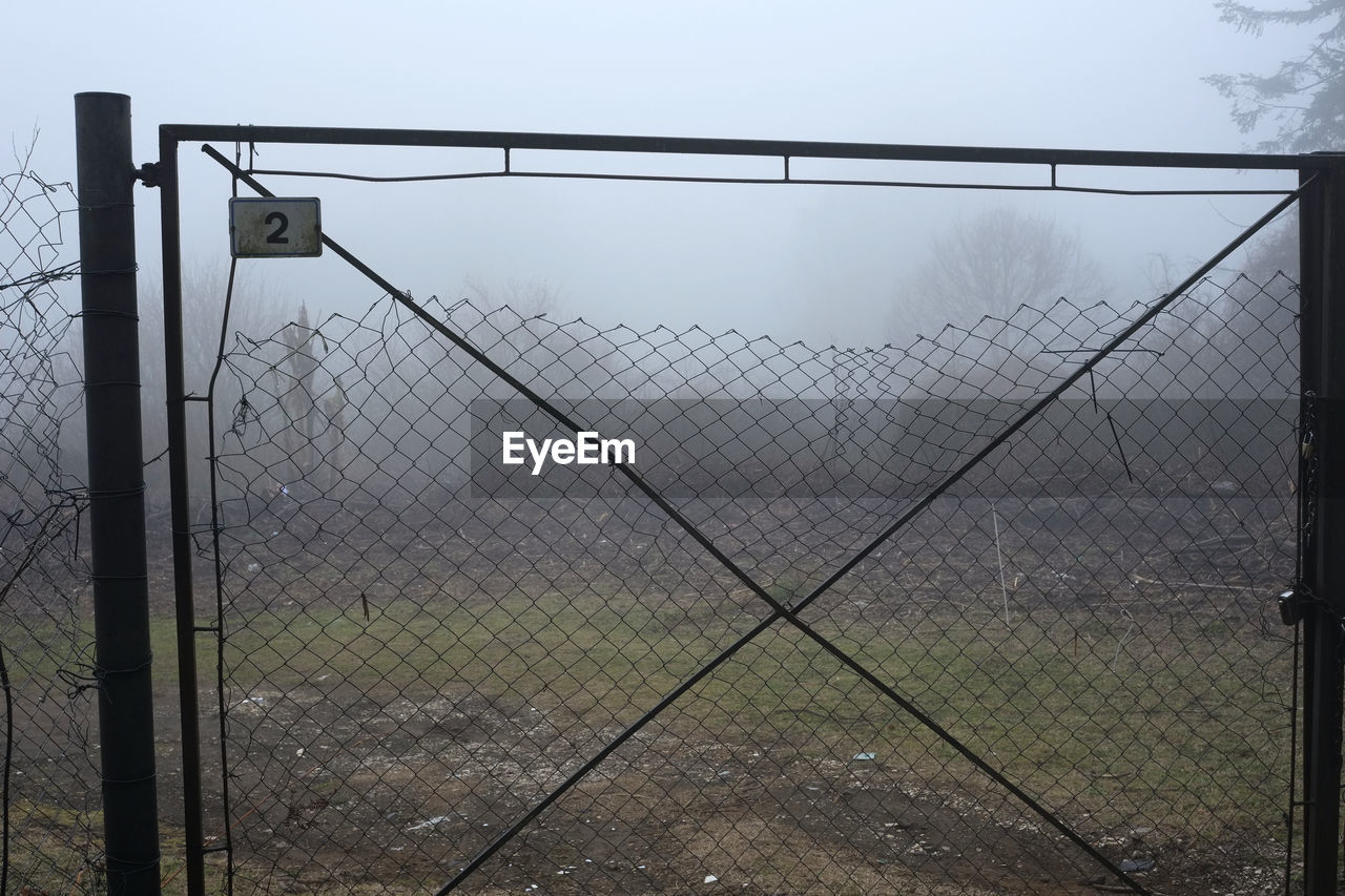 Barbed wire fence on field against sky