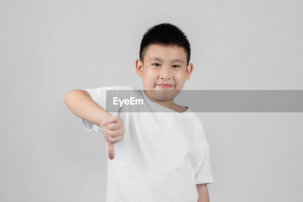 PORTRAIT OF CUTE BOY STANDING OVER WHITE BACKGROUND