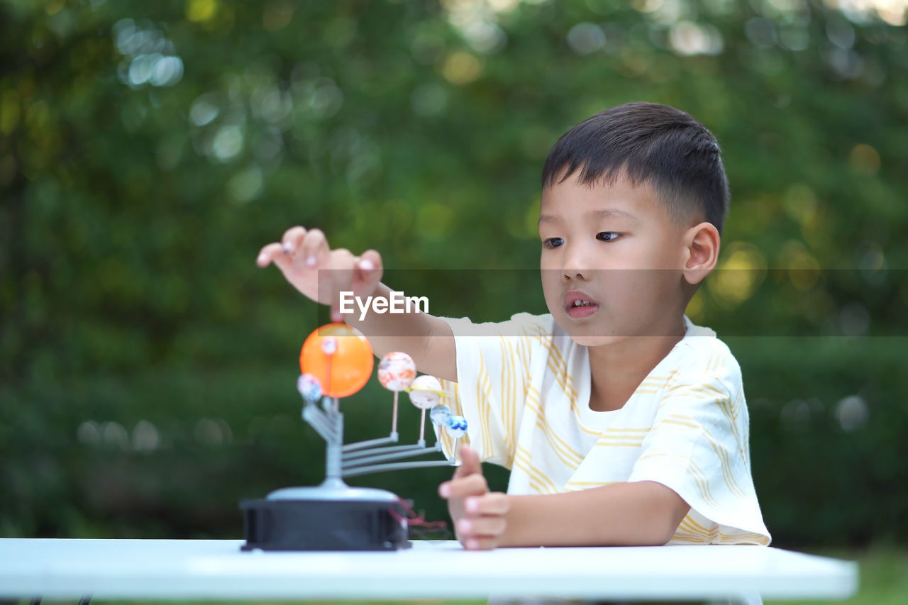 Close-up of cute boy playing with model on table in park