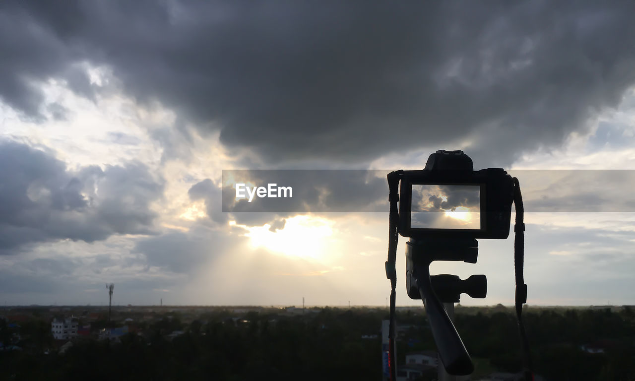 CAMERA PHOTOGRAPHING AGAINST SKY AT SUNSET