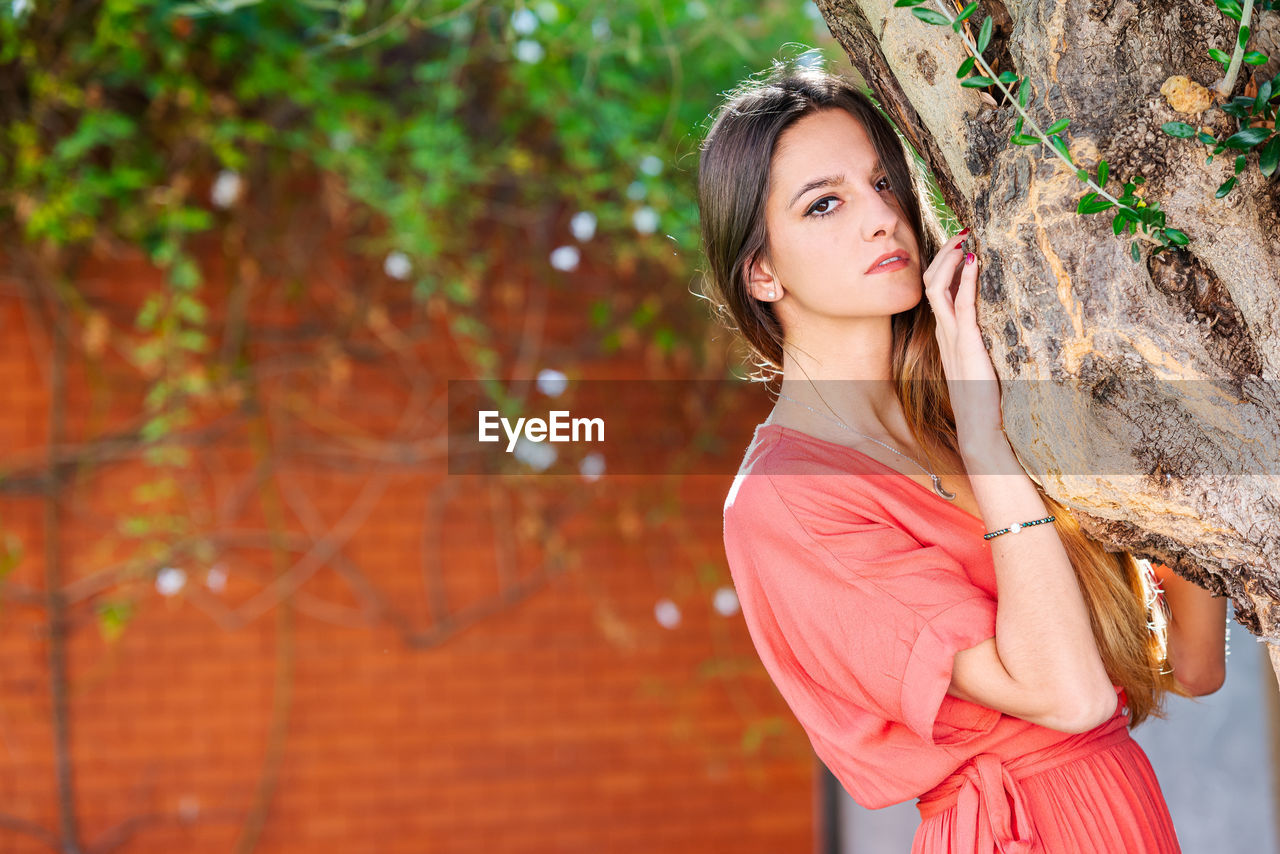 Portrait of woman standing by tree