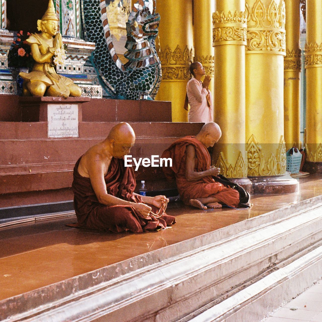 MAN SITTING ON STATUE IN TEMPLE